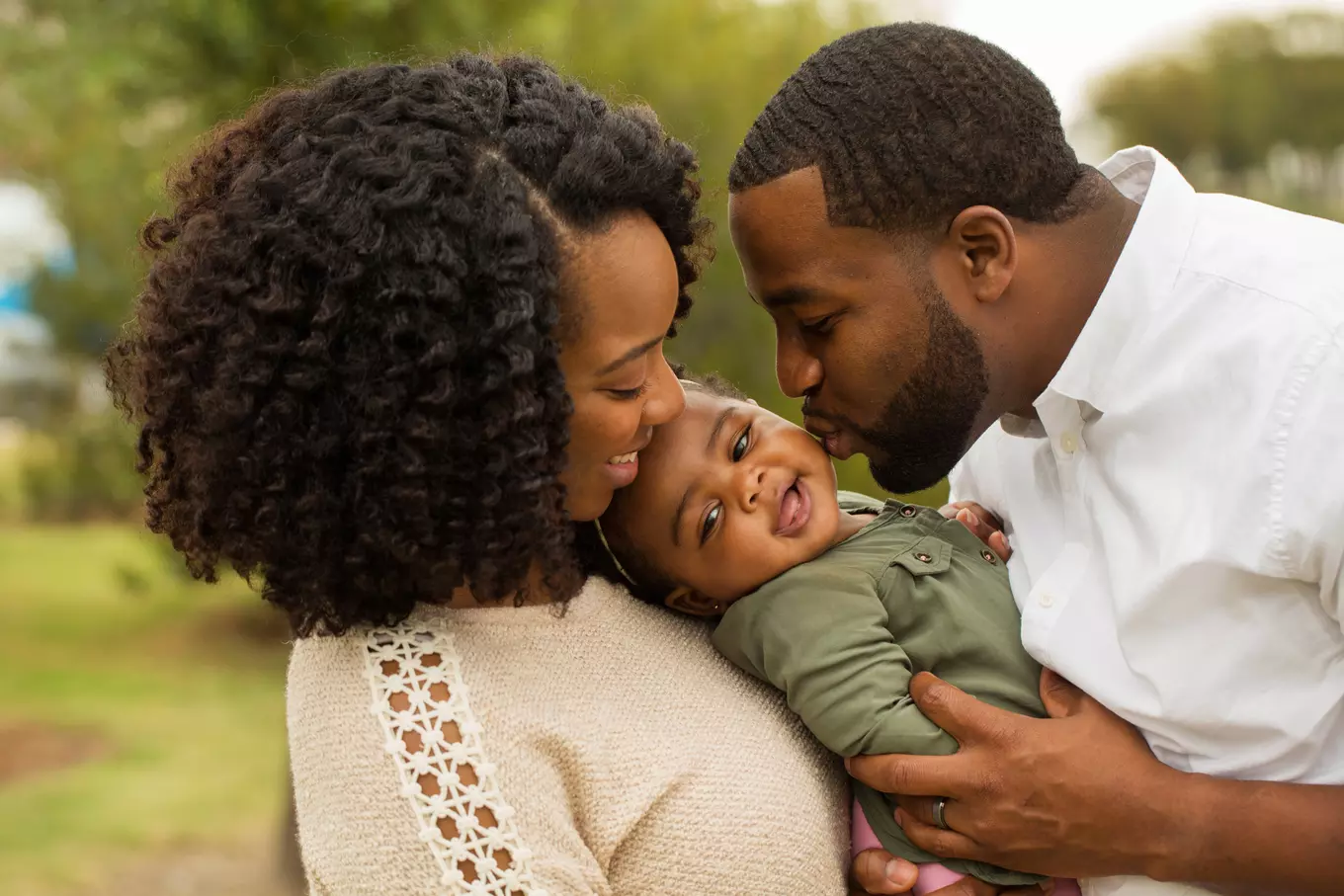 A photo of a black couple holding a cute baby.