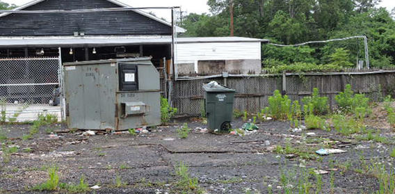 Commercial parking lot in need of maintenance, trash and weeds