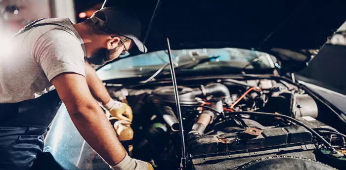 Car Repair Illegal Home Business, man leaning over engine of car working